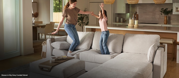 Family jumping on a grey Lovesac sectional couch