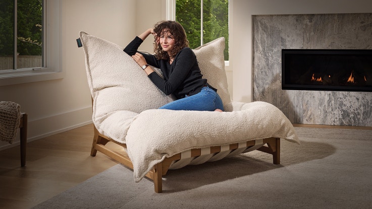 A woman sitting in a Lovesac PillowSac Accent Chair in her living room.