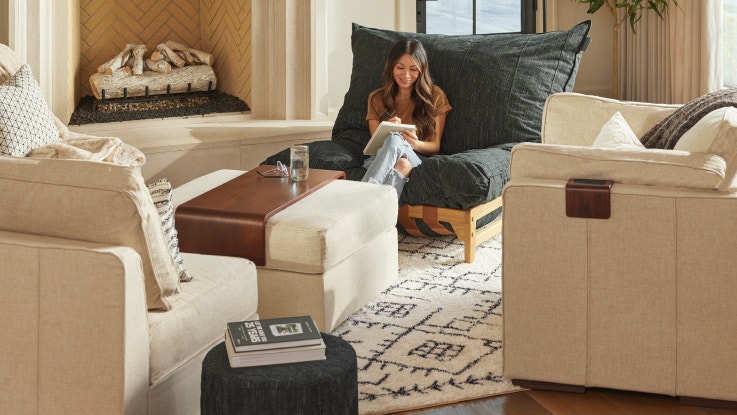 A woman sitting in a Lovesac PillowSac Accent Chair in her living room.